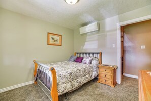 A bedroom with a bed, a nightstand, a dresser, a framed picture on the wall, and an air conditioning unit. - 1/2 Mi to Buffalo Thunder Resort: Spacious Retreat (Santa Fe)