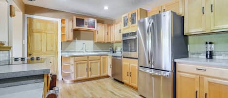 A kitchen with wooden cabinets, stainless steel appliances, and a tiled backsplash.