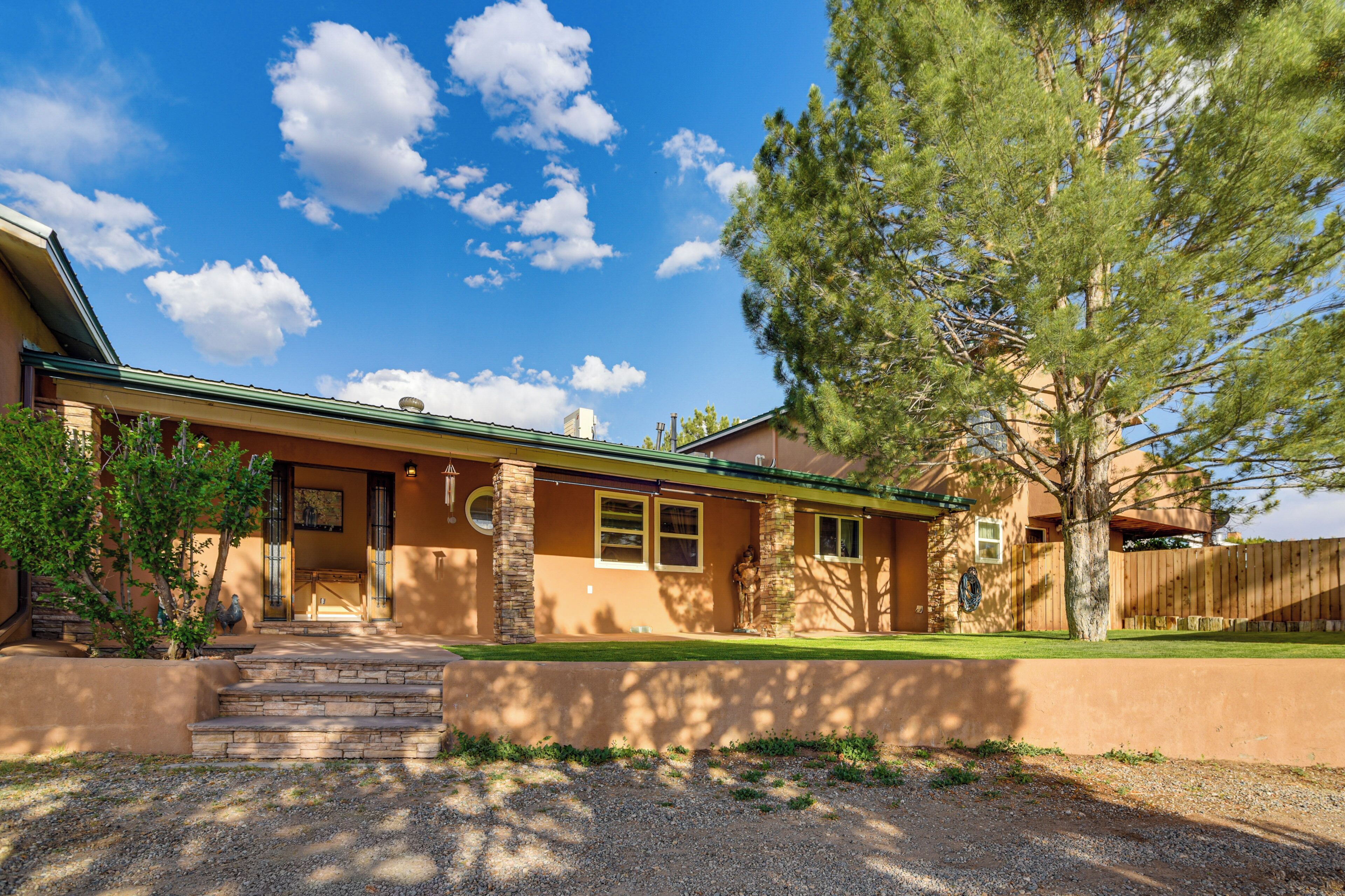 A house with a front porch, a wooden fence, and a large tree.