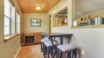 A kitchen with wooden cabinets, a refrigerator, and a dining area with a table and stools.