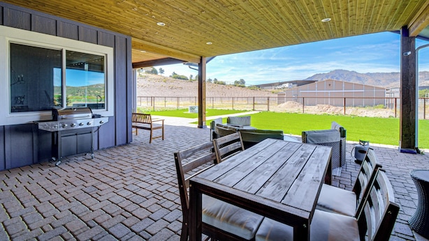 Eine Außenpatio mit Grill, Sitzgelegenheiten und Blick auf die Landschaft.