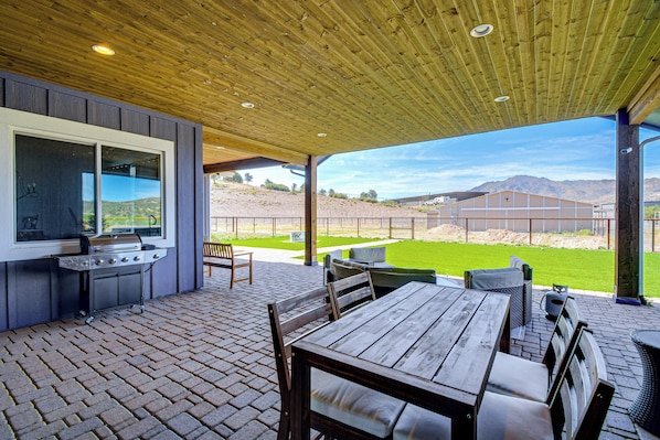 Eine Außenpatio mit Grill, Sitzgelegenheiten und Blick auf die Landschaft.