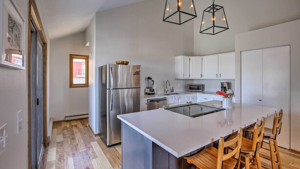 A modern kitchen with a central island, stainless steel appliances, white cabinetry, and wooden chairs. - Modern Condo w/ Balcony & Bbq, 6 Mi to Winter Park (Fraser)