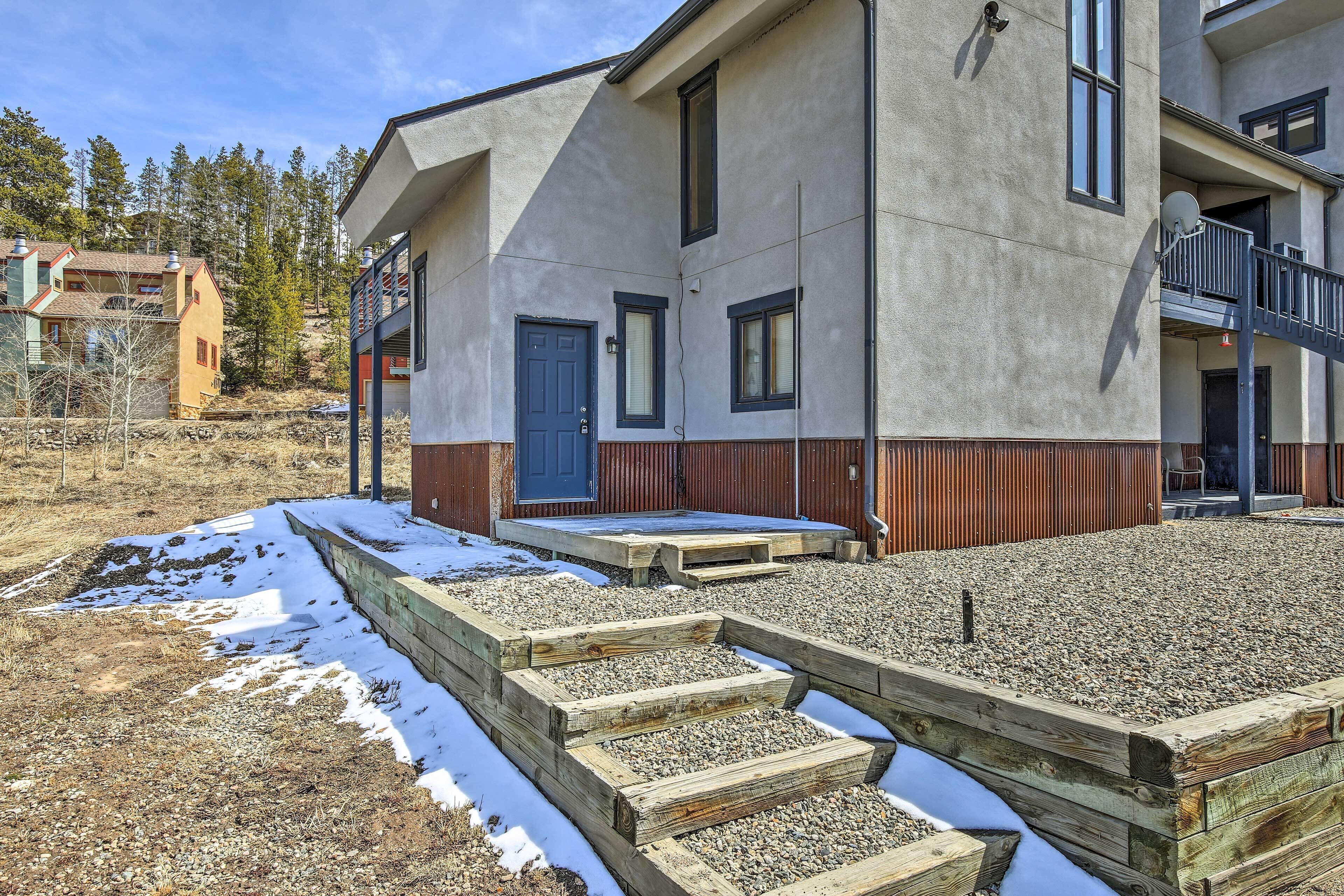A modern building with a flat roof, a blue door, and a balcony.