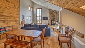A spacious living area with a wooden ceiling, stone wall, and a large window. - Modern Condo w/ Balcony & Bbq, 6 Mi to Winter Park (Fraser)