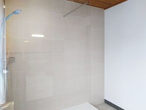 A modern bathroom with a glass shower enclosure, a visible showerhead, and a tiled floor. - Le Village by Interhome (Meuvaines)
