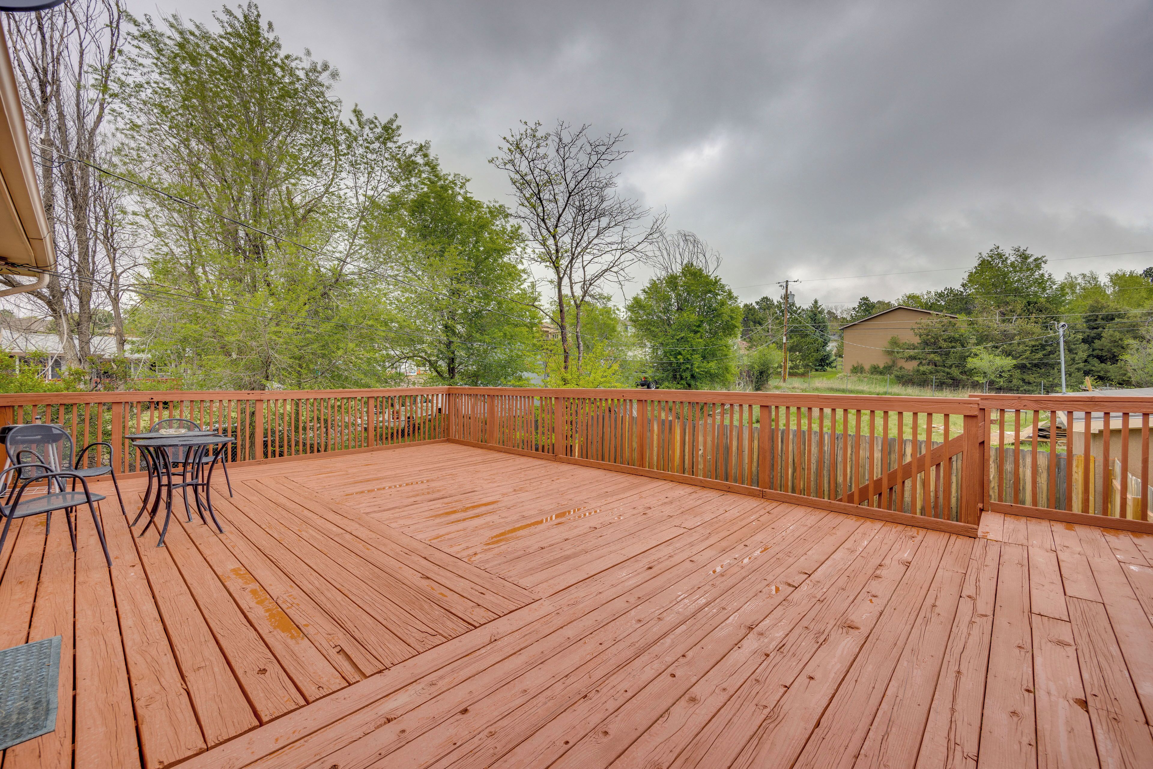 A wooden deck with a railing, a table, and chairs.