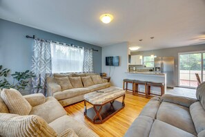Una sala de estar con un sofá, una mesa de centro y una zona de cocina con nevera y armarios.