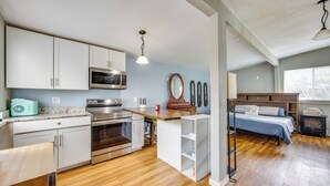 A compact kitchen with modern appliances, a wooden dining table, and a cozy bedroom with a bed and dresser. - Couples Outdoor Retreat Near Garden of the Gods (Colorado Springs)
