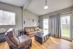 A living room with a leather sofa, a coffee table, a window with blinds, a ceiling light, and a sliding glass door. - Couples Outdoor Retreat Near Garden of the Gods (Colorado Springs)