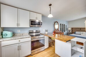 A kitchen with white cabinets, a microwave, an oven, a wooden countertop, and a hanging light fixture. - Couples Outdoor Retreat Near Garden of the Gods (Colorado Springs)