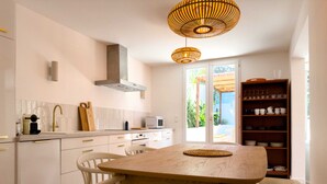 Une cuisine moderne avec des meubles blancs, une table à manger en bois et un luminaire suspendu.