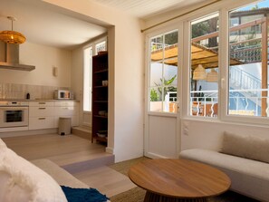 A modern kitchen with built-in appliances, a dining area with a round wooden table, and a view of a balcony with outdoor furniture. - Calanca - Niolon - Renovated, sea view, 1 min walk (Le Rove)