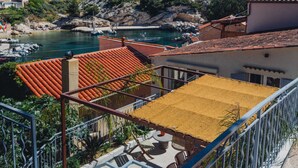 Une vue sur la côte, avec un balcon donnant sur un port de plaisance, une colline parsemée de bâtiments et un ciel bleu dégagé.