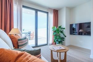 Una sala de estar moderna con un sofá, una mesa de centro, un televisor y un balcón con una planta.