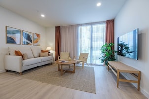 Una sala de estar moderna con un sofá, dos sillones, una mesa de centro y un televisor.
