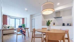 Una cocina moderna con una mesa redonda de madera, una lámpara colgante y una planta en maceta.