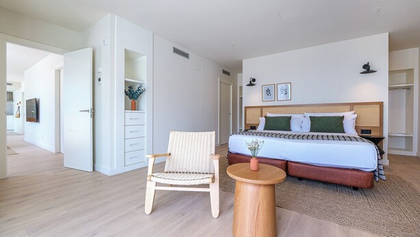 Un dormitorio con cama, una silla, una mesa redonda y un armario.