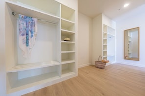 A spacious room with a large walk-in closet featuring multiple shelves and a hanging rod.