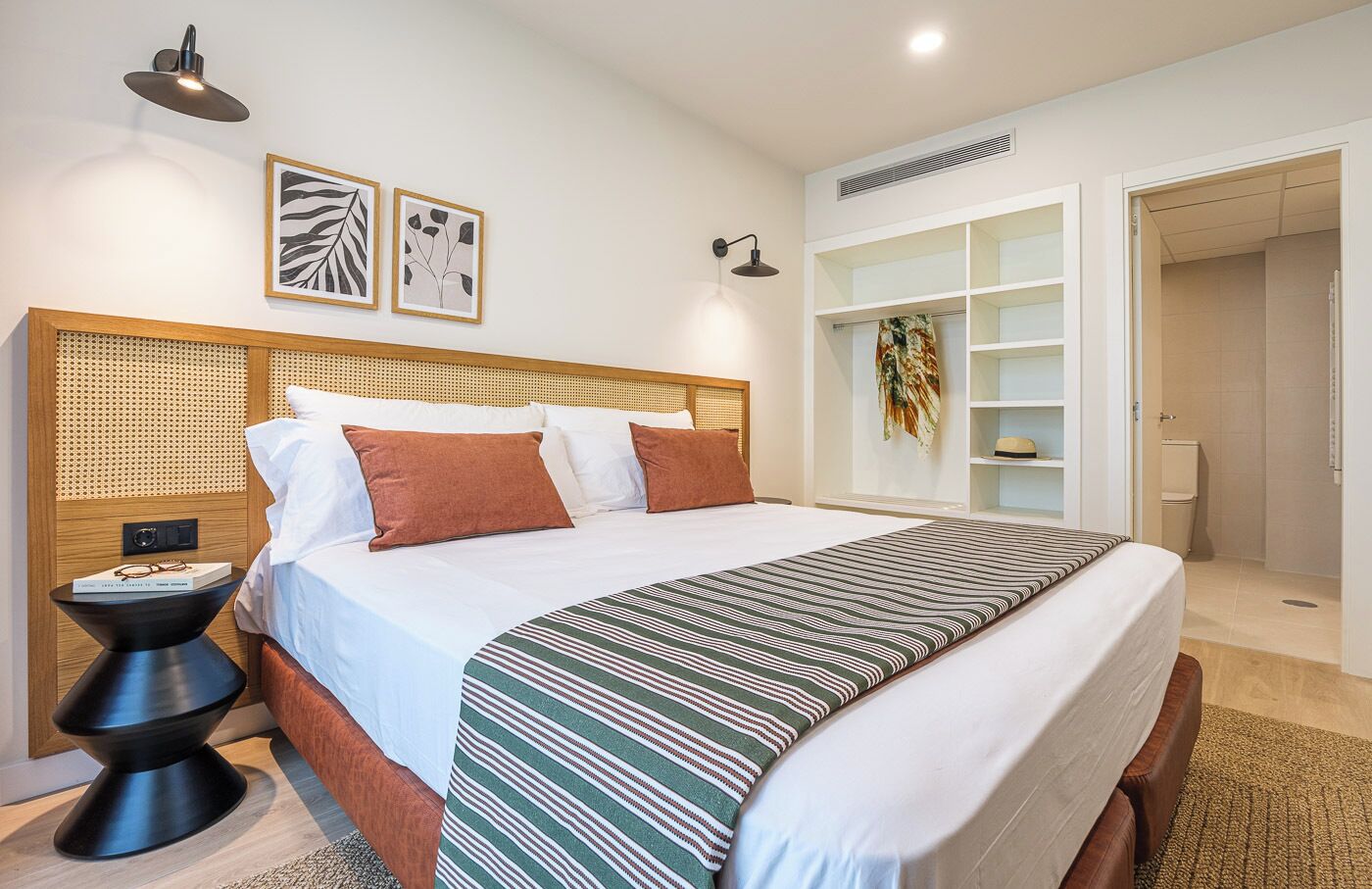 Une chambre à coucher moderne avec un grand lit, des tables de chevet, une armoire et des œuvres d’art accrochées au mur.