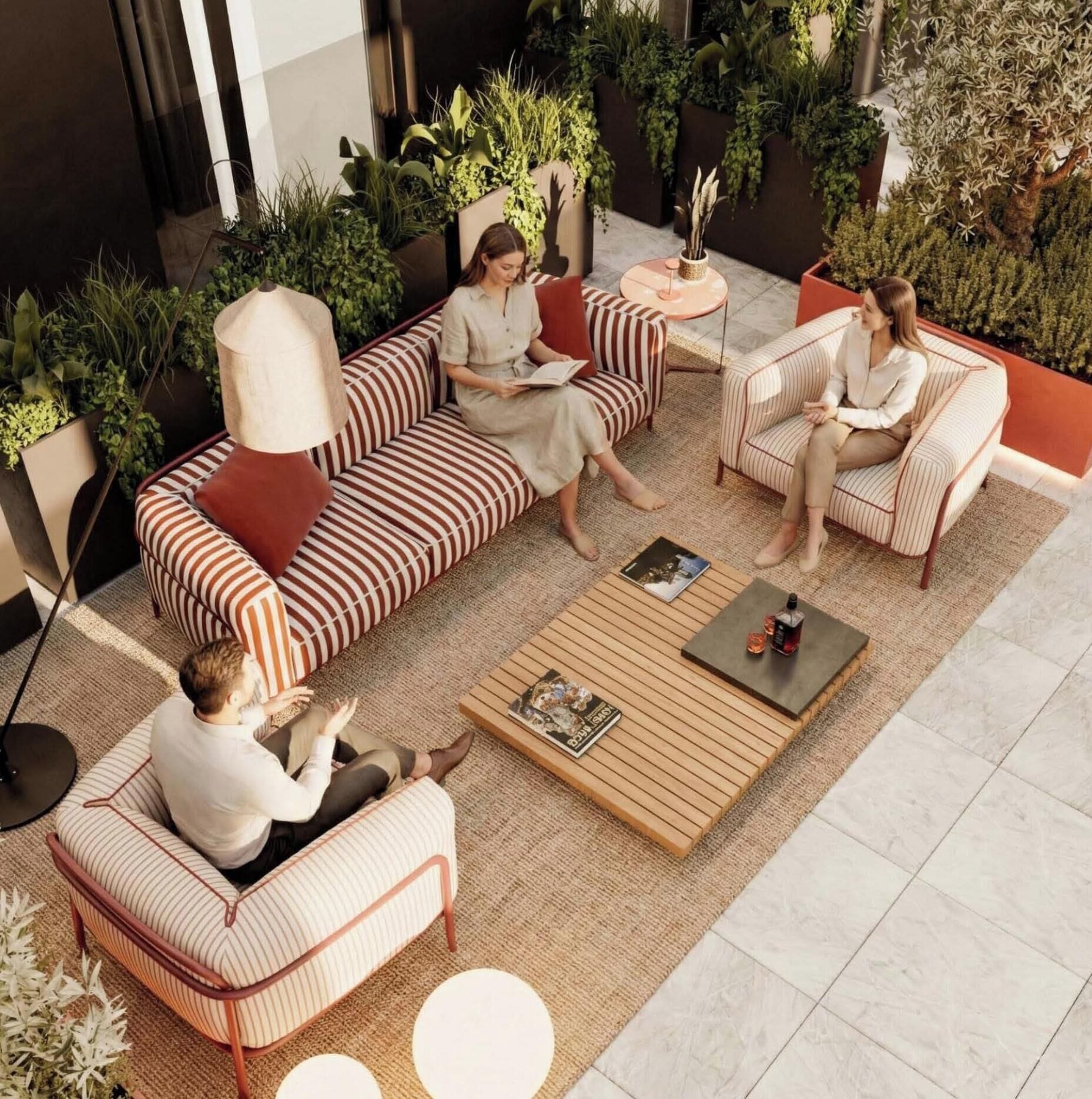 An outdoor seating area with striped sofas and a coffee table, surrounded by greenery and plants.