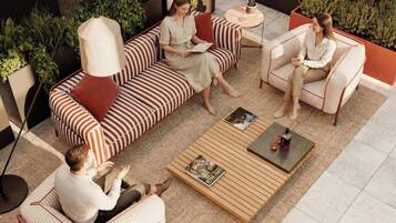 An outdoor seating area with striped sofas and a coffee table, surrounded by greenery and plants.