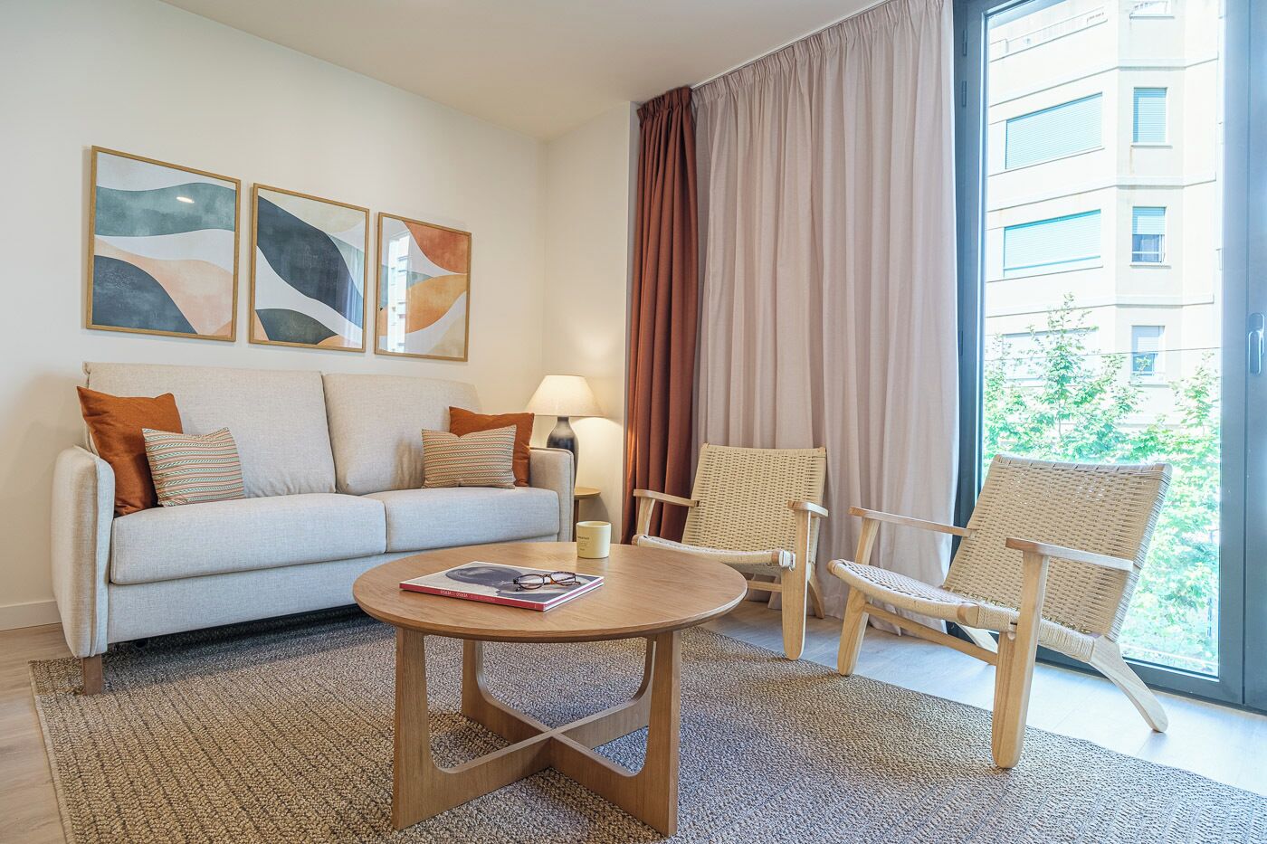 Ett modernt hotellrum med en soffa, två fåtöljer, ett soffbord och konstverk på väggen.