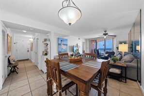 A dining area with a wooden table and chairs, a ceiling fan, and a view of the outdoors. - Buena Vista 304 (Gulf Shores)