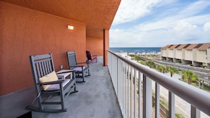 A balcony with rocking chairs and a view of the beach and hotel buildings. - Buena Vista 304 (Gulf Shores)