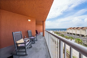 Ein Balkon mit Schaukelstühlen und Blick auf Strand und Hotelgebäude.