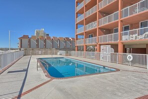 A rooftop pool area with a swimming pool, a white fence, and a multi-story building with balconies in the background. - Buena Vista 304 (Gulf Shores)