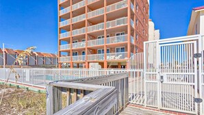 A multi-story building with balconies, a wooden deck, and a gated entrance. - Buena Vista 304 (Gulf Shores)