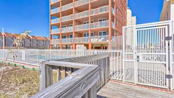 A multi-story building with balconies, a wooden deck, and a gated entrance.