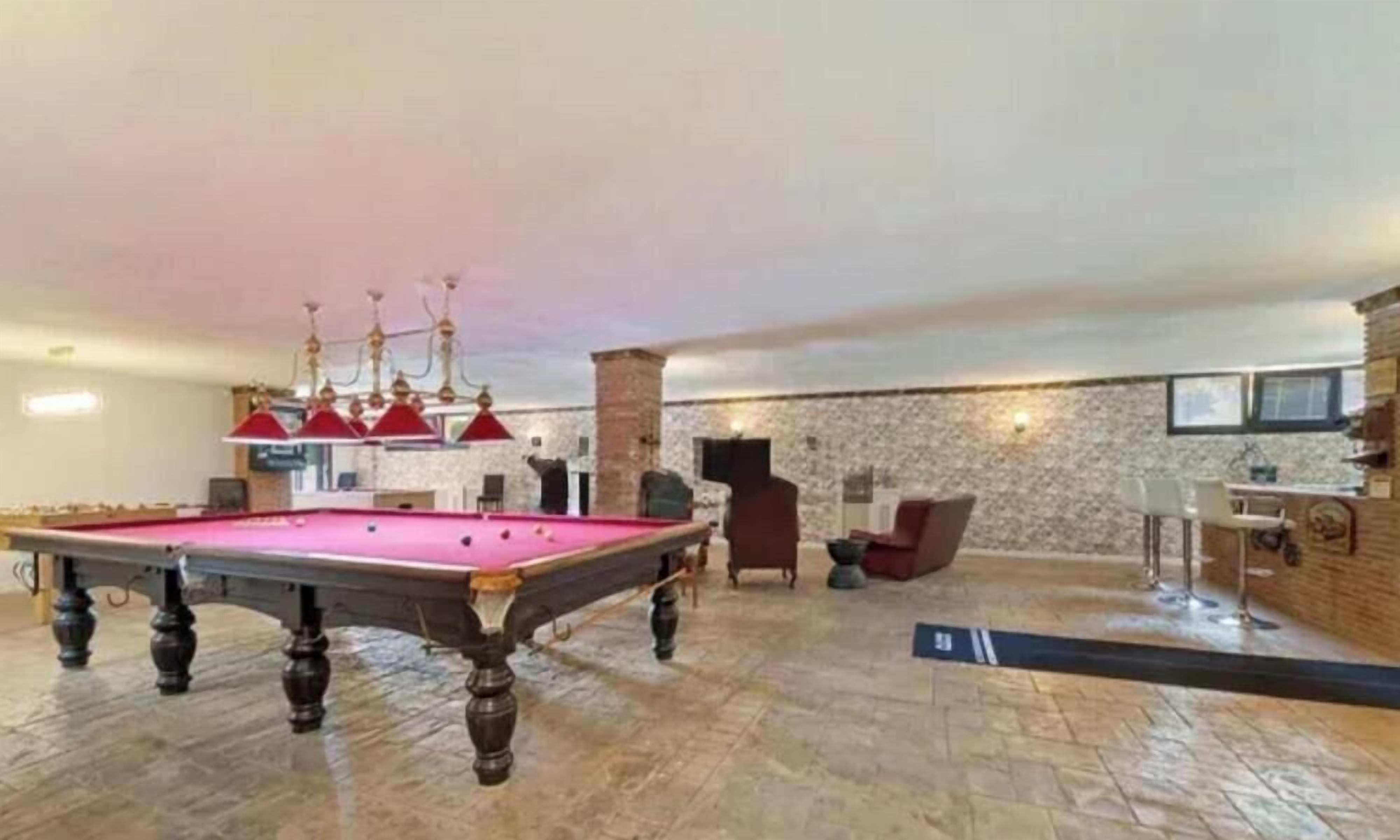 A spacious indoor area with a pool table, a fireplace, and a stone wall.