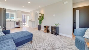 A modern living room with a blue sofa, a patterned rug, a potted plant, and a small cabinet. - Rooftop Deck + Private Patio! West Seattle Home (Seattle)