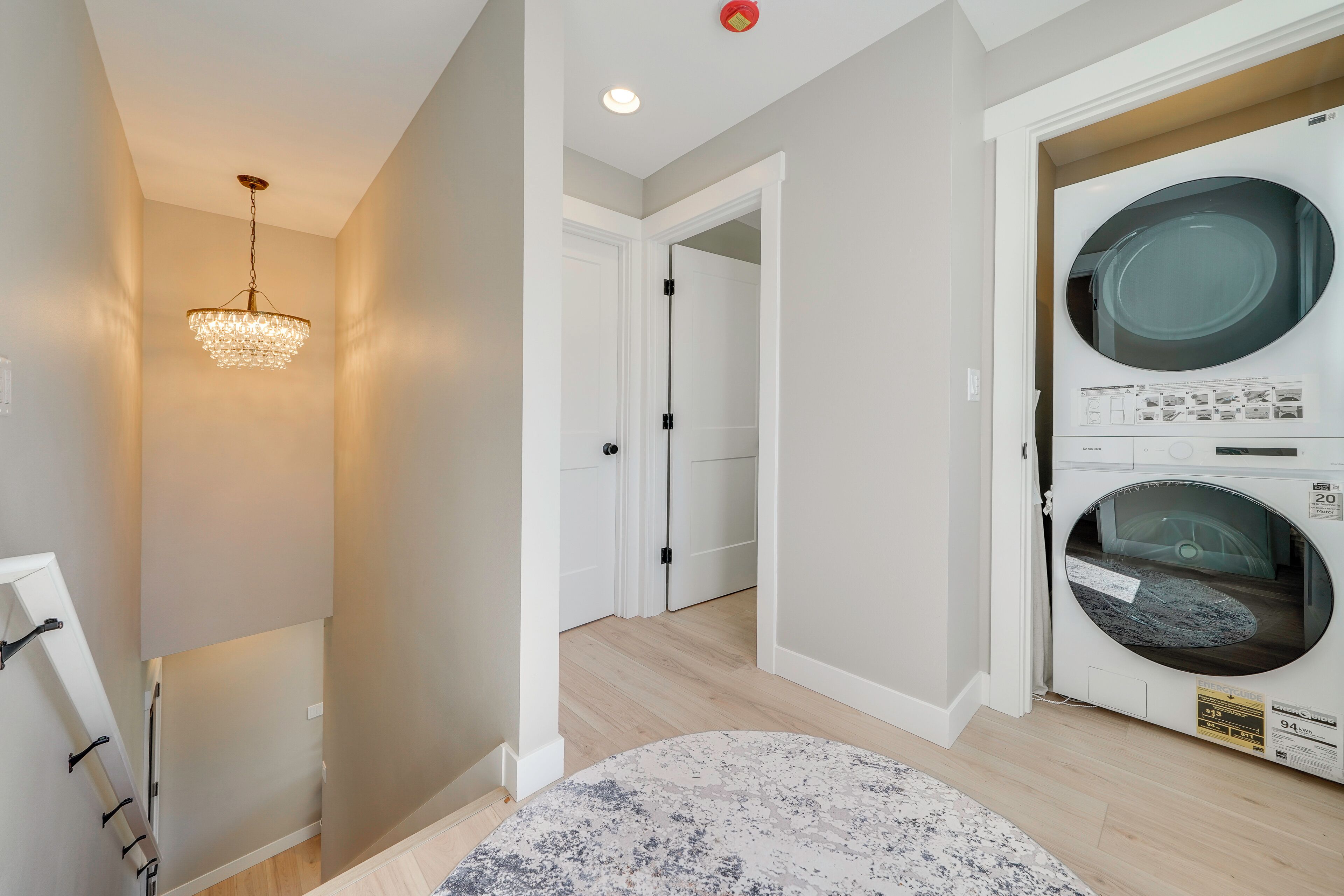 A laundry room with a washing machine, a dryer, and a chandelier.