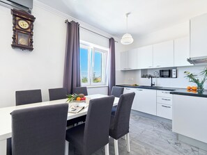 Uma cozinha moderna com armários brancos, micro-ondas e uma área de jantar com mesa e cadeiras.