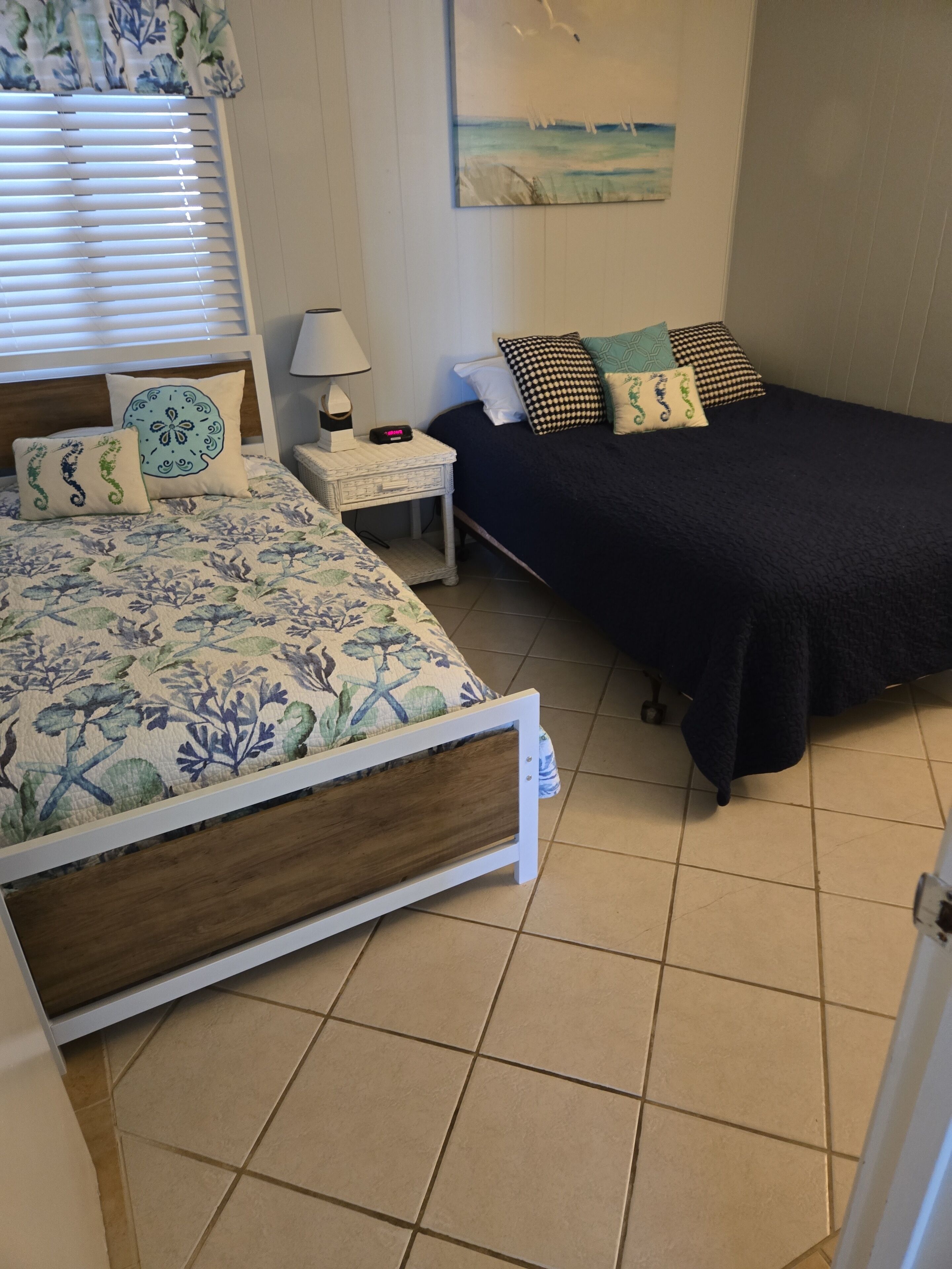 A bedroom with a bed, bedside table, lamp, and a painting on the wall.
