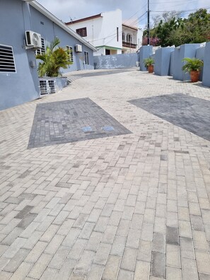 A paved courtyard with a blue building, air conditioning units, and potted plants. - Enjoyable 1-bedroom apartment with AC in charming Willemstad (Willemstad)