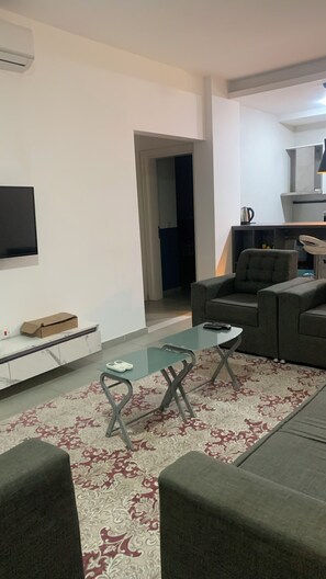 Un salon moderne avec un canapé, une table basse en verre et un téléviseur fixé au mur.