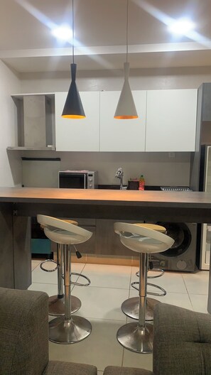 Eine moderne Küche mit einer Kochinsel, Barhocker, einer Mikrowelle und einem eingebauten Backofen.