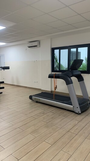 Une pièce équipée d’un tapis de course, d’une fenêtre offrant une belle vue et d’un plafond doté d’un éclairage encastré.