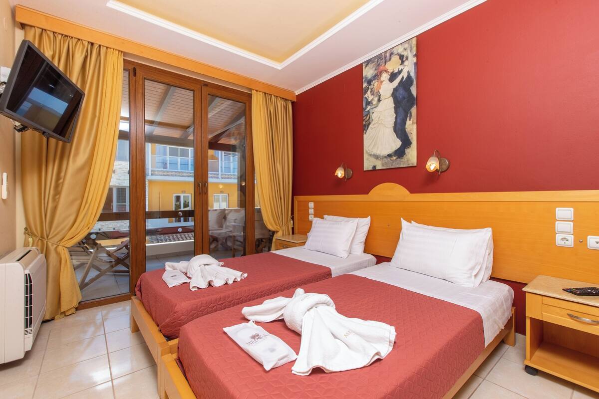 Une chambre d’hôtel avec deux lits, une télévision, un tableau et une vue sur l’extérieur.