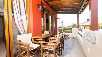 An outdoor patio with wooden furniture, a red wall, and a view of the surrounding area.