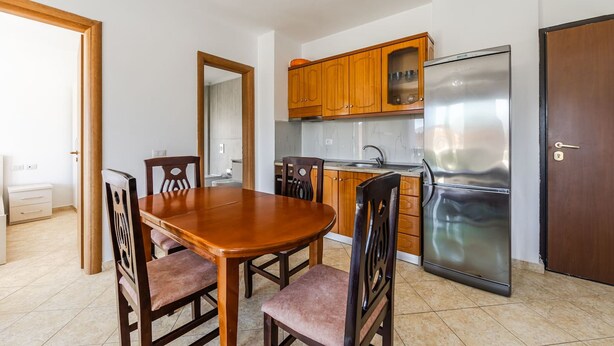 A compact kitchen with wooden cabinets, a stainless steel refrigerator, and a dining table with chairs. - Orikum Beachside Retreat Apartment 2 (Orikum)