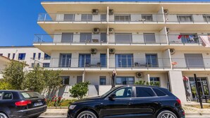 A multi-story building with balconies, air conditioning units, and a parked car. - Orikum Beachside Retreat Apartment 2 (Orikum)