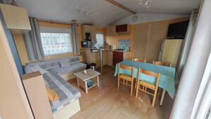 En kompakt bolig med tekøkken, spiseplads og sofa.