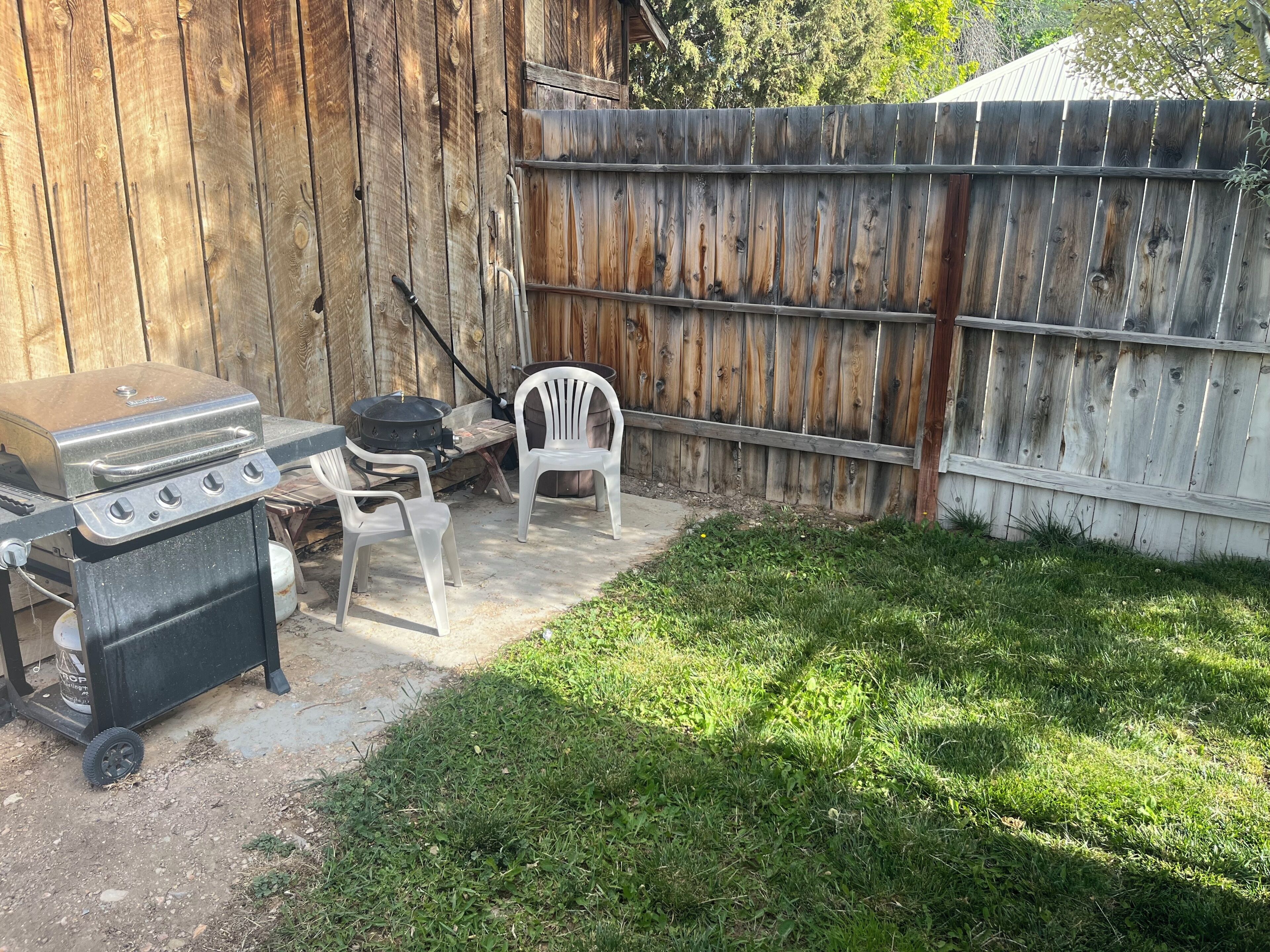 A backyard with a grill, a barbecue, and a chair.