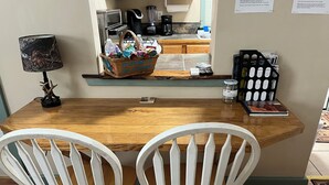 A wooden dining table with two white chairs, a basket labeled 'WELCOME TO THE GIFTAWAY,' and a coffee maker on the counter. - Stan's Hideaway in Tropic 9 miles to Bryce Canyon, Tucked away & private, Unique (Tropic)
