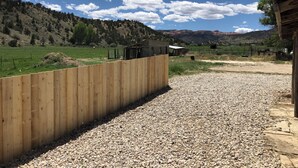 A gravel path leading to a wooden fence and a rustic building, with a mountainous landscape in the background. - Stan's Hideaway in Tropic 9 miles to Bryce Canyon, Tucked away & private, Unique (Tropic)